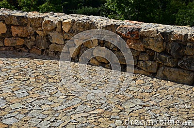 Beautifully folded retaining wall of rough stone joined with cement mortar. brown beige yellow irregular limestone stone. holding Stock Photo