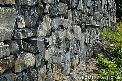 Beautifully folded retaining wall of rough stone joined with cement mortar. brown beige yellow irregular limestone stone. holding Stock Photo