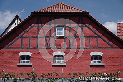 Beautifully renovated cowshed with red half-timbered facade and red roof under a blue sky Stock Photo