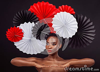 Beauty is beauty, whatever your background. Studio shot of a beautiful young woman posing with a origami fans against a Stock Photo