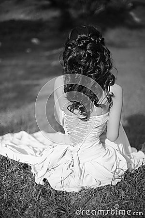 beauty black and white portrait. Brunette bride resting and sitting on green grass at spring park. Stock Photo