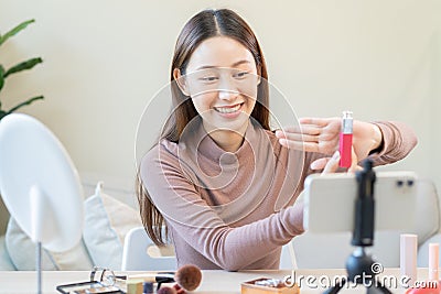 Beauty blogger, asian young woman, girl vlogger makeup face, showing, reviews cosmetics products while recording video, tutorial Stock Photo
