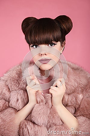 Beauty bun hairstyle. Fashion teen girl model in pink fur coat. Stock Photo