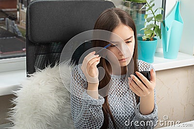 Beauty and care. A young girl combs and shares her eyelashes with a special brush Stock Photo