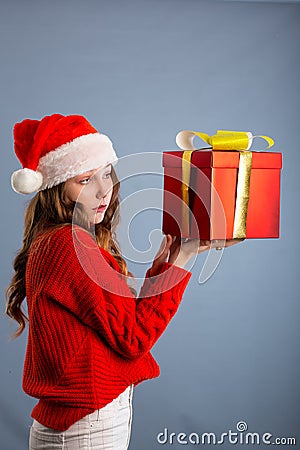 Beauty Christmas fashion model girl holding Xmas gift box. Beautiful lady, Long straight flying hair, red santa hat, holding gift Stock Photo