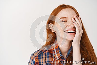 Beauty. Close-up of happy young woman with red natural hair and pale skin, smiling joyfully and covering half of face Stock Photo