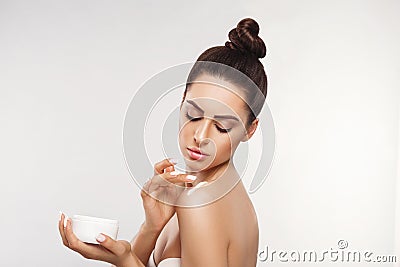 Beauty Concept. Woman Applying Cosmetics Cream, Spreads it on her shoulder to moisturize her skin and Smiling. Stock Photo