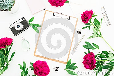 Beauty decorated concept. Blogger or freelancer workspace desk with clipboard, notebook, retro camera, peonies and pen on white ba Stock Photo