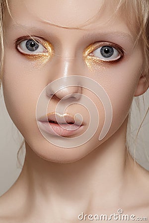 Beauty & fashion. Girl model face with bright holiday gold make-up, clean skin Stock Photo