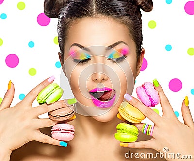 Beauty fashion model girl taking colorful macaroons Stock Photo