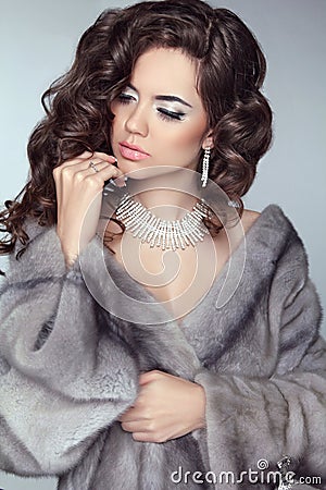 Beauty Fashion Model Woman in Mink Fur Coat. Winter Brunette Girl in Luxury clothes. Long wavy hair. Makeup. Jewelry. Stock Photo