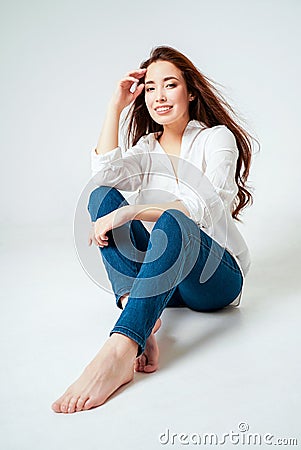 Beauty fashion portrait of smiling sensual asian young woman with dark long hair in white shirt on white background Stock Photo