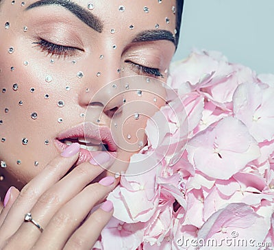 Beauty fashion Woman face decorated with gem stones, crystals. Closeup Portrait with Hydrangea. Model girl with holiday makeup Stock Photo