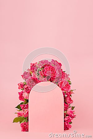 Beauty fresh pink roses as framing of arch on pink stage mockup for display cosmetic, goods, advertising, design of poster, card. Stock Photo