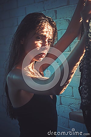 Beauty girl with natural look and healthy skin. Woman in black bodysuit at window. Woman with long wet or oily hair Stock Photo