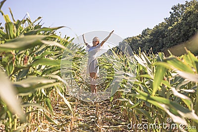 Beauty girl on summer corn field over blue clear sky. Happy young healthy woman enjoying nature outdoors. Running and Spinning Stock Photo