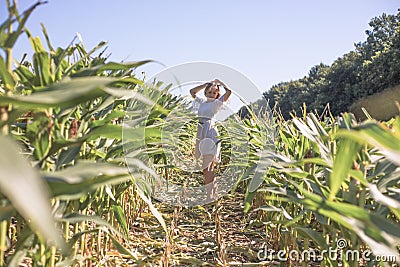 Beauty girl on summer corn field over blue clear sky. Happy young healthy woman enjoying nature outdoors. Running and Spinning Stock Photo