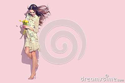 Beauty glamour girl with spring tulip flowers. Beautiful young woman posing with bouquet of tulips. Model wearing chiffon dress Stock Photo