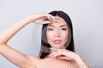 Beauty, health woman concept. Young pretty chinese lady is touching gently her attractive healthy skin of the face with fingers Stock Photo