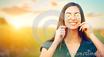 Beauty joyful girl with daisy flowers on her eyes enjoying nature and laughing on summer field Stock Photo