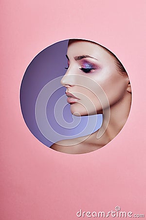 Beauty makeup cosmetics nature fashion woman in a round hole circle in pink paper, copy space advertising. Professional makeup Stock Photo