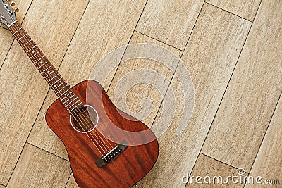 Beauty of musical instrument. Top view of the brown acoustic guitar lying on the wooden floor. Stock Photo