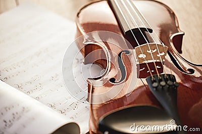Beauty of musical instruments. Close up view of brown violin lying on sheets with music notes on wooden floor. Violin Stock Photo