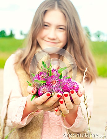 Beauty of nature. Smiling young girl holding meadow clover flowers Stock Photo