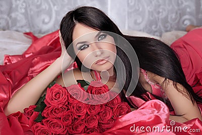 Beauty portrait. Amazing brunette woman with Red Roses lying on Stock Photo