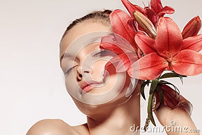 Beauty portrait of charm young girl with flower over white studio background. Cosmetics, natural beauty and Stock Photo