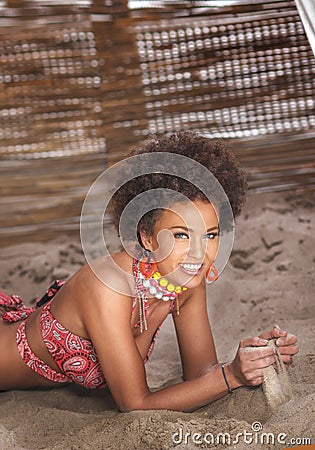 Beauty portrait of natural girl with afro lying on sand Stock Photo