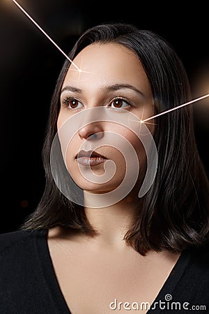 Beauty portrait of a woman with a laser beam on her cheek. The concept of laser skin rejuvenation, high-tech cosmetic procedures Stock Photo