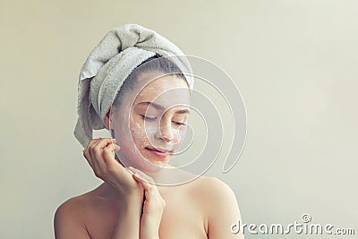 Beauty portrait of woman in towel on head with white nourishing mask or creme on face, white background isolated Stock Photo