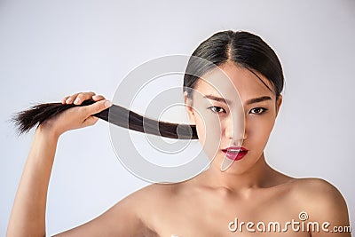 Beauty portrait of young asian woman with her hand pulling her long black hair Stock Photo