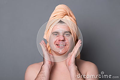 Beauty procedure and skin care. Close up portrait of calm smiling young attractive man with face mask. Stock Photo