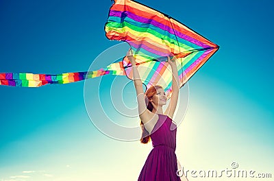 Beauty redhead girl with flying colorful kite over blue sky Stock Photo