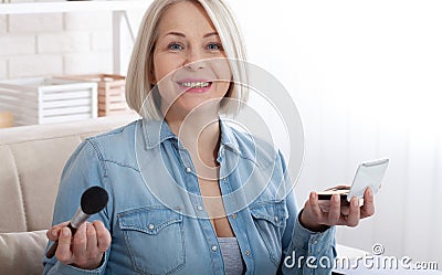 Beauty Rituals. Artistic shot of a woman immersed in the transformative process of applying makeup, accentuating her natural Stock Photo