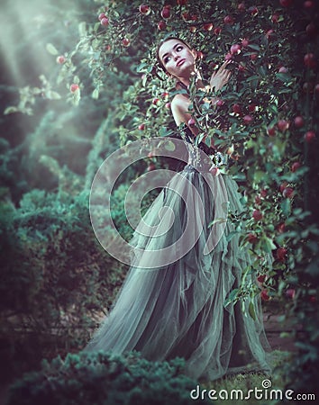 Beauty romantic model girl fashion posing in garden trees, enjoying nature in apple orchard. Beautiful brunette young woma Stock Photo