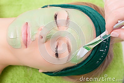 Beauty salon. Cosmetician applying facial mask at woman face. Stock Photo