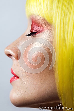 Beauty side view profile portrait of calm cute young female model with freckles, red makeup and yellow wig, closed eyes with Stock Photo