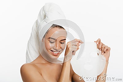 Beauty Skin Care Concept - Beautiful Caucasian Woman applying paper sheet mask on her face white background. Stock Photo