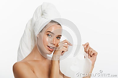 Beauty Skin Care Concept - Beautiful Caucasian Woman applying paper sheet mask on her face white background. Stock Photo
