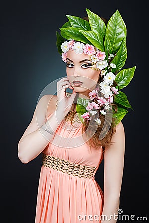 Beauty Spring girl with flowers hair. Beautiful model woman with flowers on her head. The Nature Of Hairstyle. Summer Stock Photo