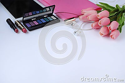 Beauty stuff. Makeup background. Aspects of makeup. Folder, tablet, tulips flowers, headphones, lipsticks and eye shadows on the t Stock Photo