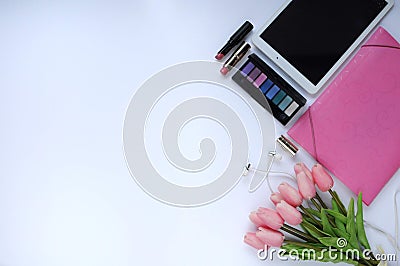 Beauty stuff. Makeup background. Aspects of makeup. Folder, tablet, tulips flowers, headphones, lipsticks and eye shadows on the t Stock Photo