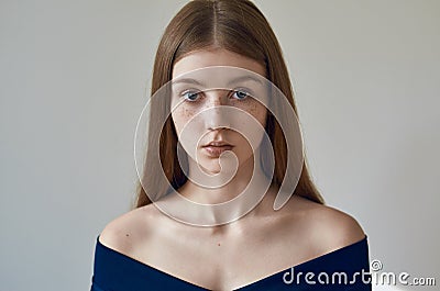 Beauty theme: portrait of a beautiful young girl with freckles on her face and wearing a blue dress on a white background in Stock Photo