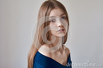 Beauty theme: portrait of a beautiful young girl with freckles on her face and wearing a blue dress on a white background in Stock Photo