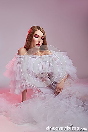 Beauty Woman bright red makeup. Art nude naked woman in a transparent light dress on a pink background. Professional bright makeup Stock Photo