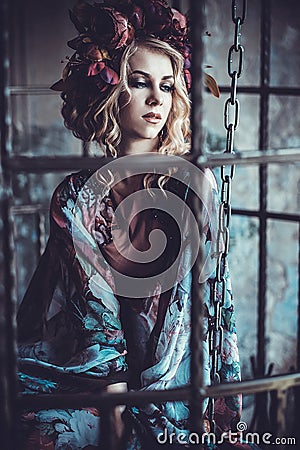 Beauty woman in the palace. Luxurious fashion stylish girl in cage. Flower dress and a wreath of flowers. Stock Photo