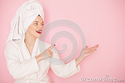 Beauty Young woman with red lips standing in the bath robe and towel on the head on the pink background. Studio shot Stock Photo